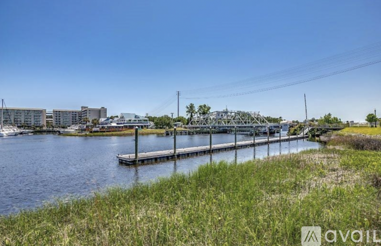 A serene waterfront scene with a bridge and buildings in the distance.