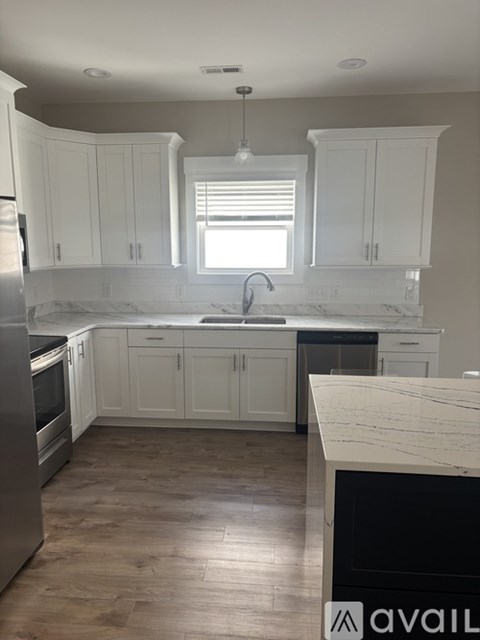 A kitchen with white cabinets and a marble countertop.