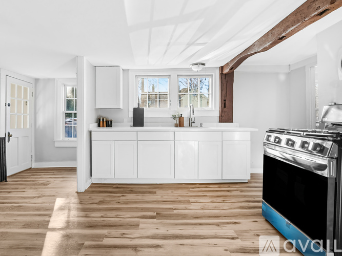 A modern kitchen with white cabinets and a wooden floor.