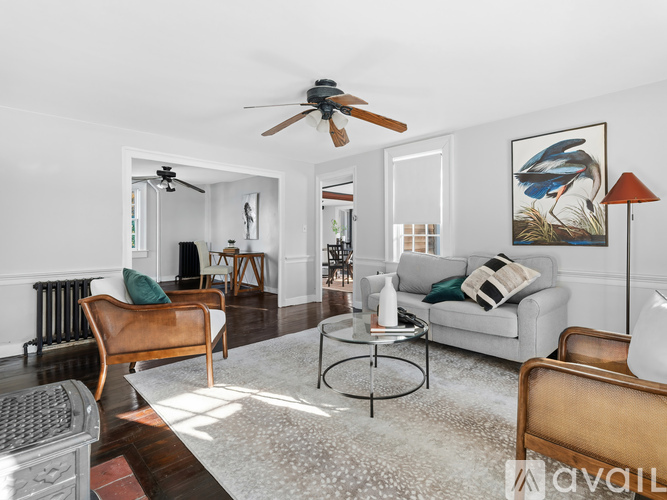 A living room with a ceiling fan and a painting of a bird on the wall.