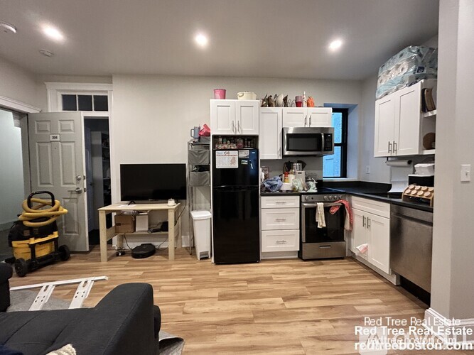 A kitchen with white cabinets and a black fridge.