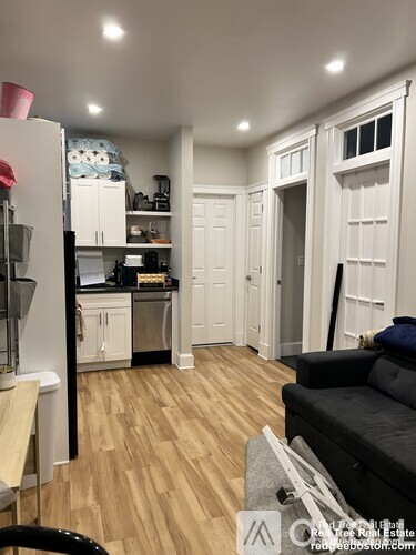 A kitchen with a refrigerator, a couch, and a dining table.