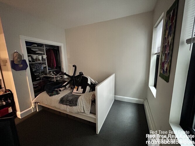 A bedroom with a bed, a closet, and a window.