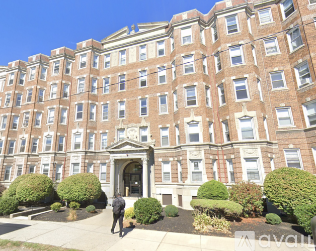 A person is standing in front of a large red brick building.