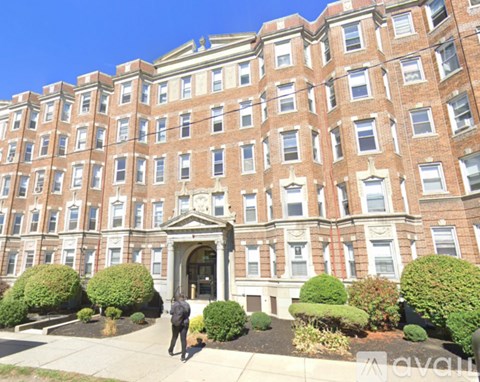 A person is standing in front of a large red brick building.