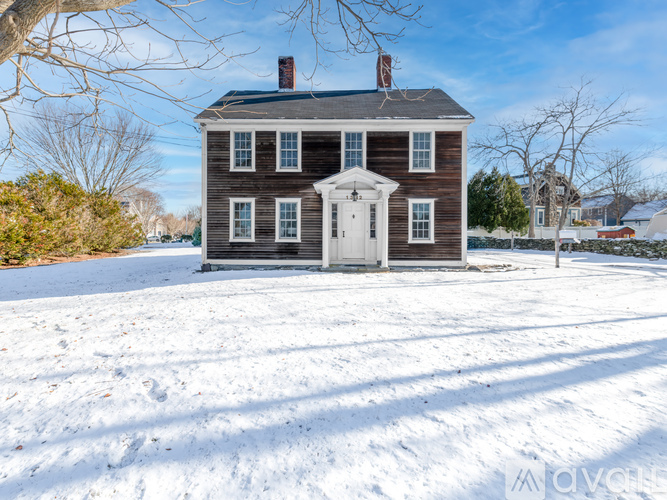 A house with a white door and windows is surrounded by snow.