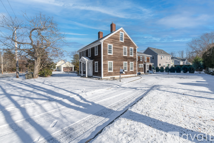 A large brown house with a white door and windows is surrounded by a snowy landscape.