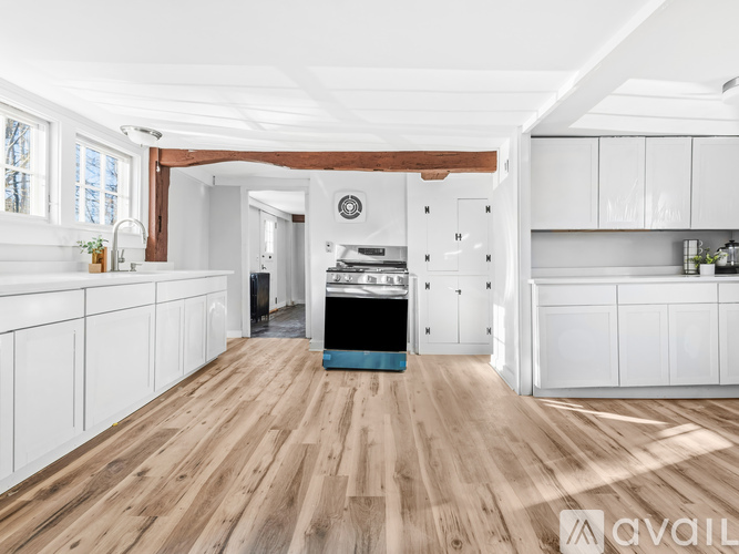 A kitchen with white cabinets and wooden floors.