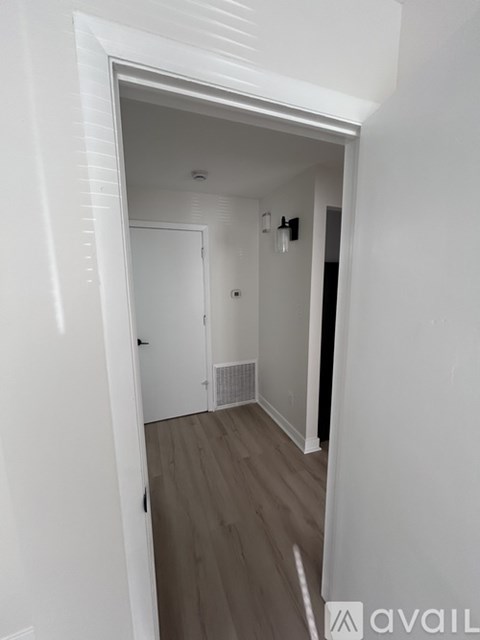 A white hallway with a door and a wall-mounted light fixture.