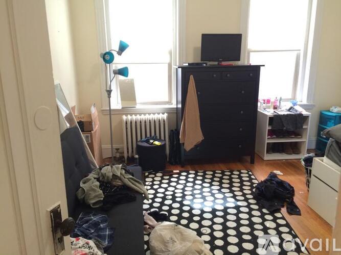 A black and white polka dot rug is on the floor of a messy room.