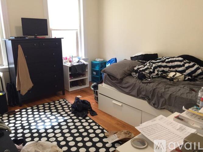 A bedroom with a bed, dresser, and a TV.