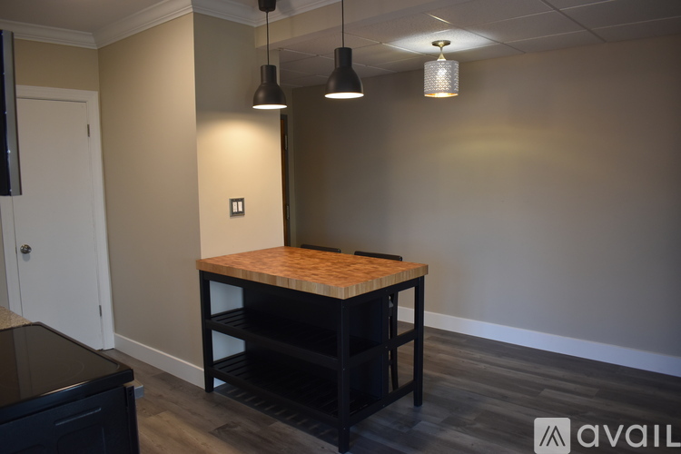 A kitchen with a table and a black trash can.