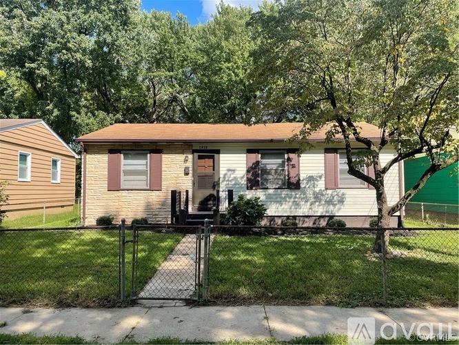 A house with a brown roof and a white fence in front of it.