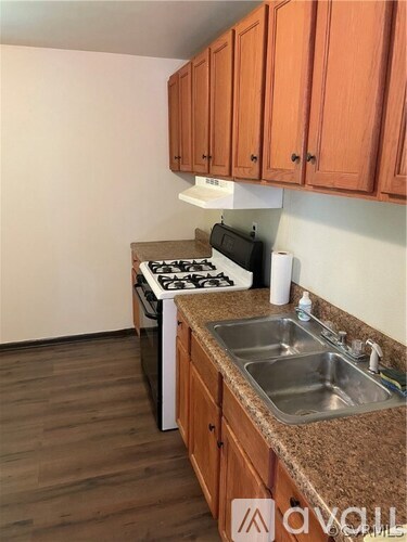 A kitchen with a stove, sink, and cabinets.