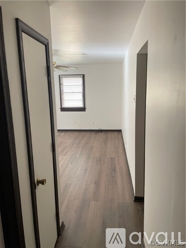 A hallway with wood floors and a door on the left.