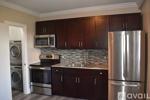 A kitchen with dark wood cabinets and a stainless steel refrigerator.