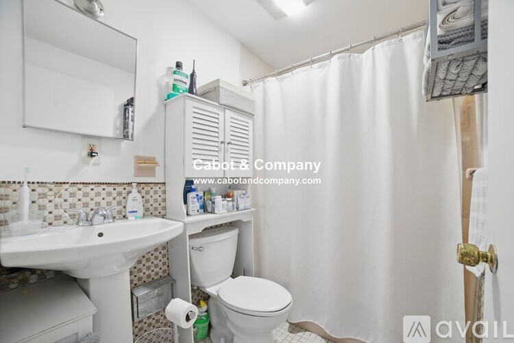 A bathroom with a white sink, toilet, and shower curtain.
