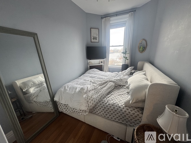 A bedroom with a bed, chair, and mirror.