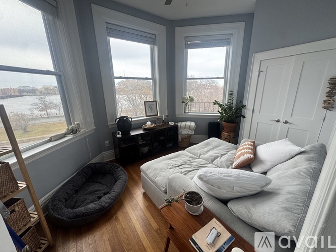 A cozy bedroom with a large bed, a window with a view, and a nightstand with a lamp.