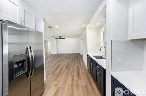 A modern kitchen with a stainless steel refrigerator and wooden flooring.