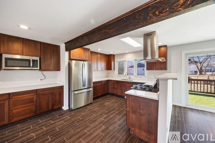 A kitchen with wooden cabinets and a stainless steel refrigerator.