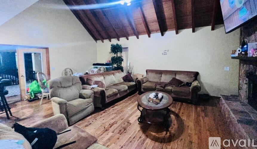 A living room with a wooden floor and a large flat screen TV mounted on the wall.