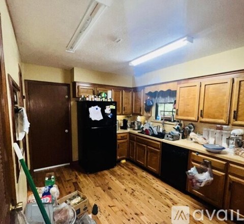 A kitchen with wooden cabinets and a black fridge.