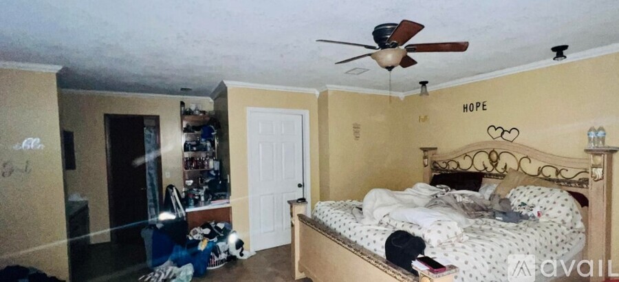 A bedroom with a bed, a ceiling fan, and a wall with the word "HOPE" written on it.