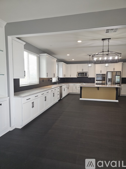 A spacious kitchen with white cabinets and a central island.