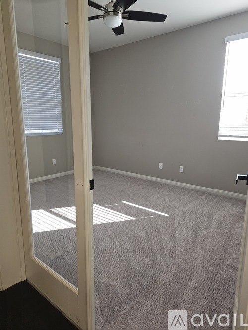 A room with a ceiling fan and a door leading to another room.