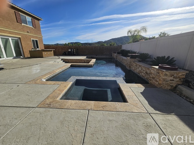 A sunny day at a house with a pool and a hot tub.