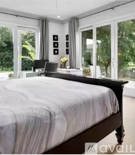A bedroom with a large bed and a desk with a chair.
