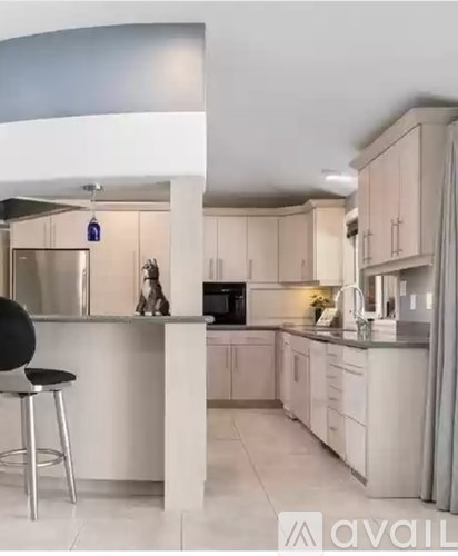 A modern kitchen with white cabinets and a black bar stool.
