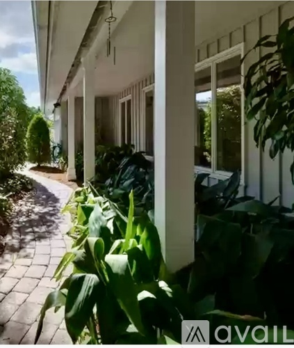 A white building with a balcony and plants in front.