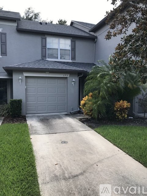 A house with a grey garage door and a driveway leading to it.