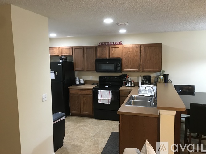 A kitchen with a black refrigerator and wooden cabinets.