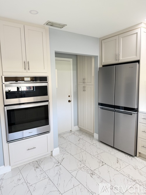 A kitchen with a refrigerator, oven, and cabinets.