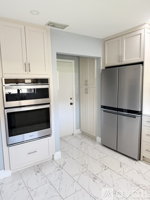 A kitchen with a refrigerator, oven, and cabinets.