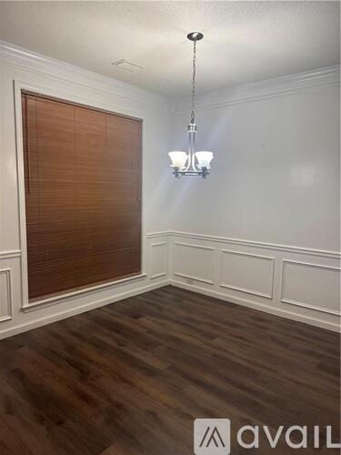 A room with wooden floors and a chandelier hanging from the ceiling.