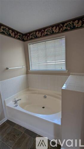 A bathroom with a bathtub and a window with blinds.
