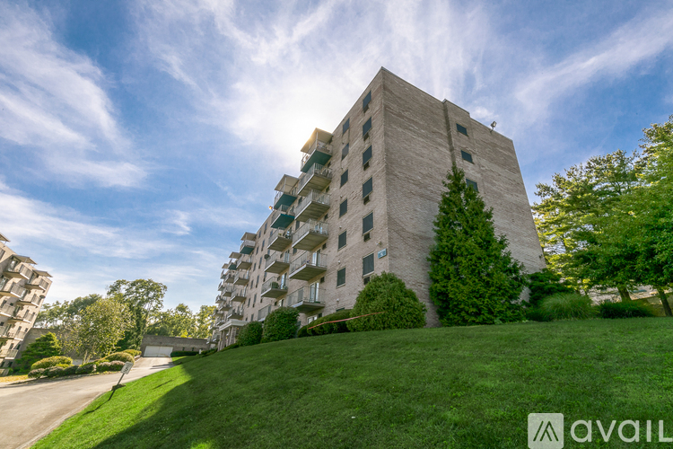 A tall residential building with a green lawn in front.