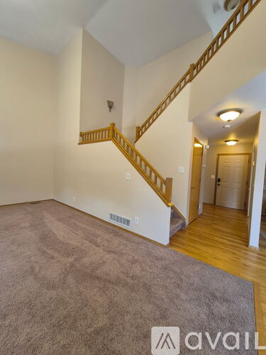 A room with a carpeted floor and a staircase with wooden railings.