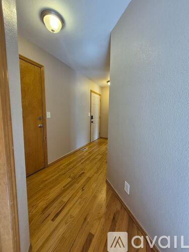 A hallway with wooden floors and white walls.