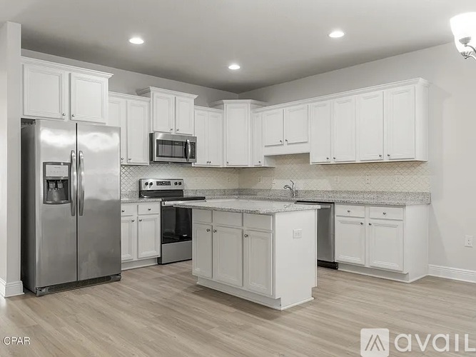 A kitchen with white cabinets and a stainless steel refrigerator.