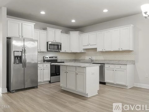 A kitchen with white cabinets and a stainless steel refrigerator.
