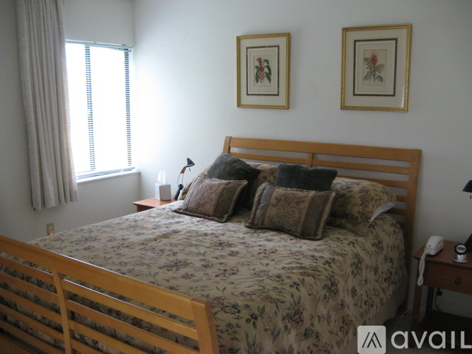 A bedroom with a bed, nightstand, and two pictures on the wall.