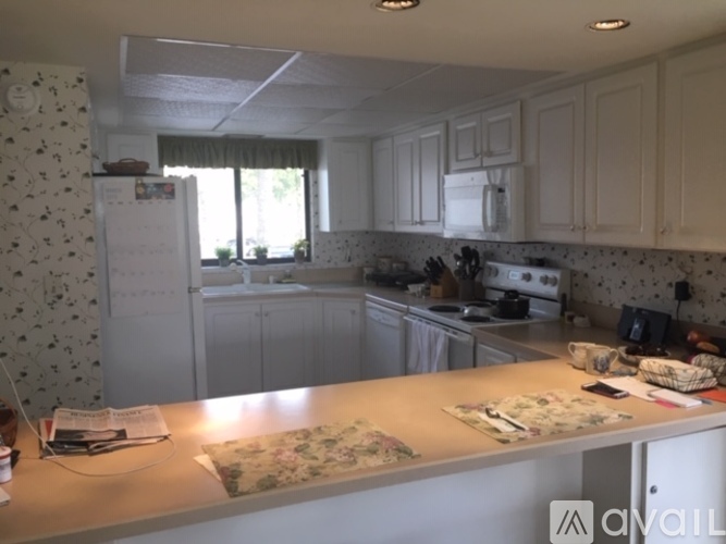 A kitchen with white cabinets and a patterned wallpaper.
