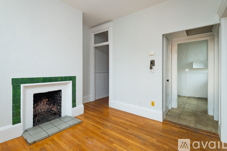 A room with a fireplace and a doorway leading to another room.