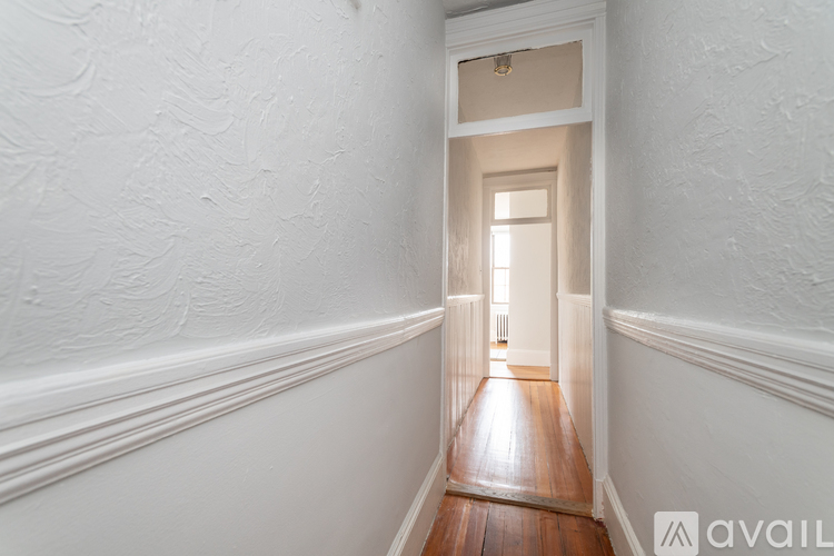A hallway with a wooden floor and white walls.