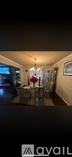 A dining room with a table set for four and a chandelier hanging from the ceiling.